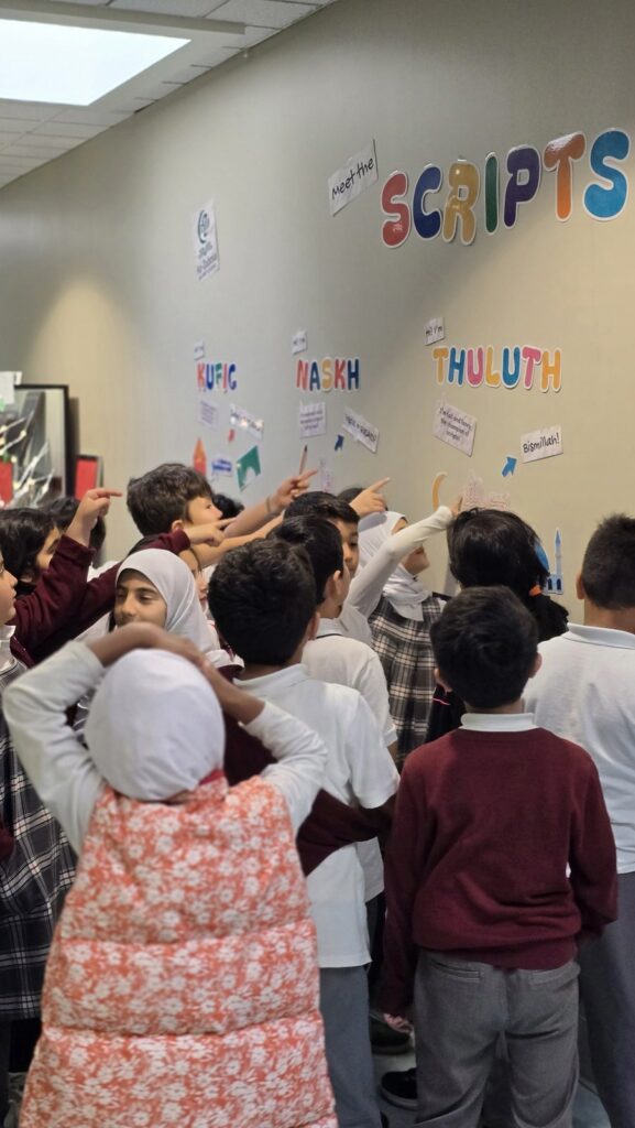 Students pointing at the wall under the SCRIPTS! title during their class visit