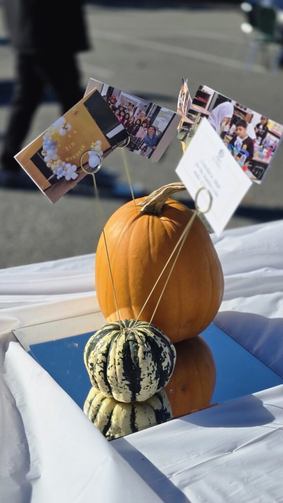 A pumpkin and gourd table decoration with photos of school life